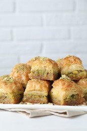 Photo of Delicious fresh baklava with chopped nuts on white table, closeup. Eastern sweets