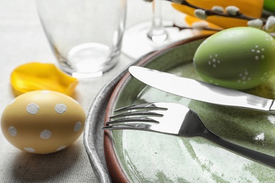 Festive Easter table setting with painted eggs on light background, closeup