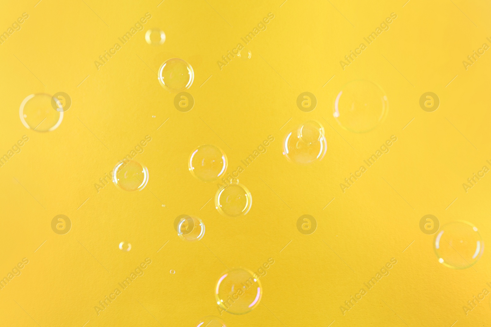 Photo of Beautiful transparent soap bubbles on yellow background