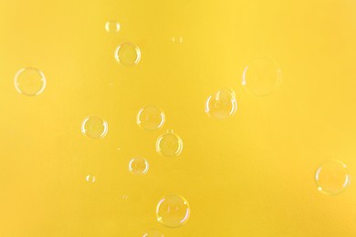 Photo of Beautiful transparent soap bubbles on yellow background