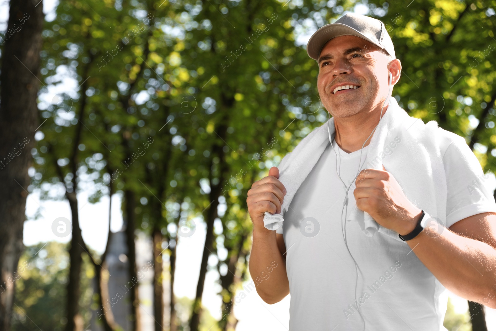 Photo of Handsome mature man with towel in park, space for text. Healthy lifestyle