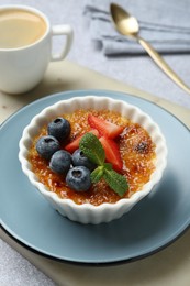 Photo of Delicious creme brulee with berries and mint in bowl on grey table, closeup