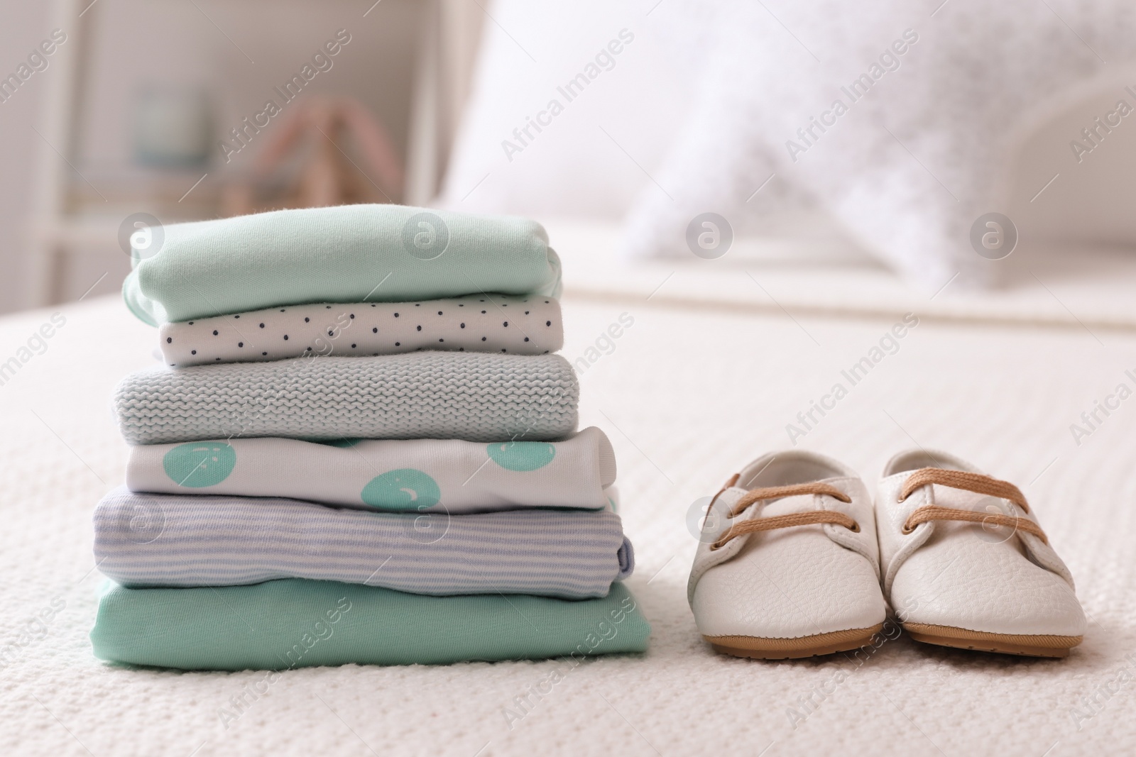 Photo of Stack of baby boy's clothes and shoes on bed at home, space for text