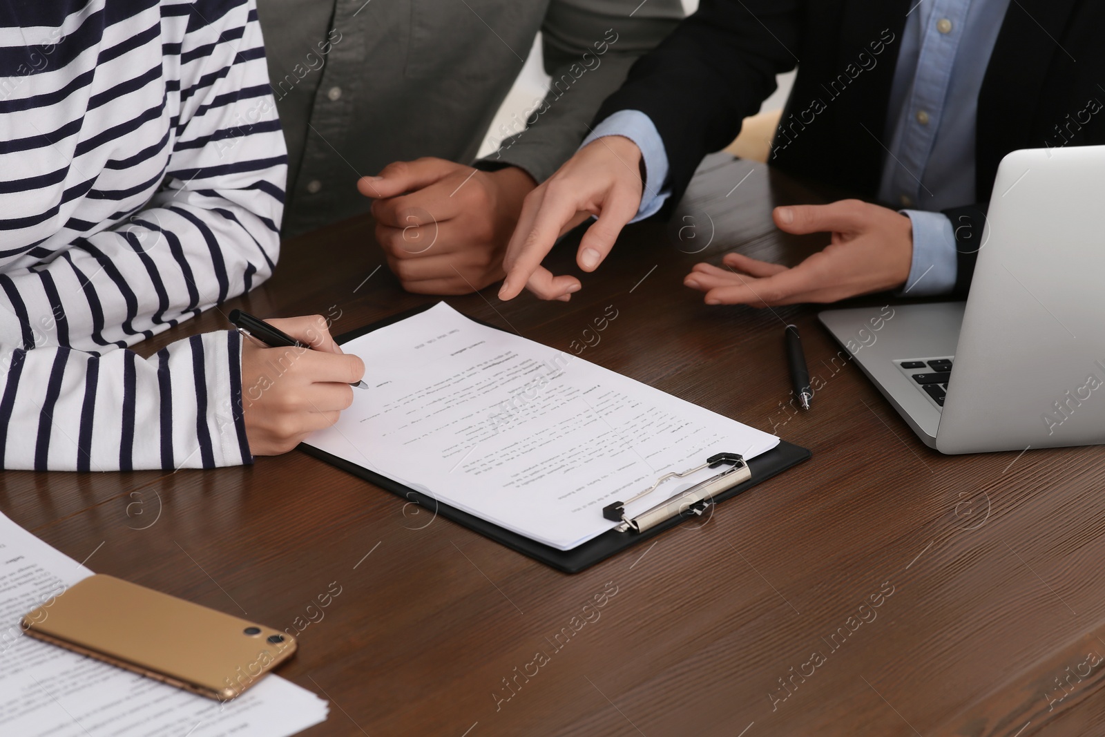 Photo of Notary working with couple at wooden table, closeup