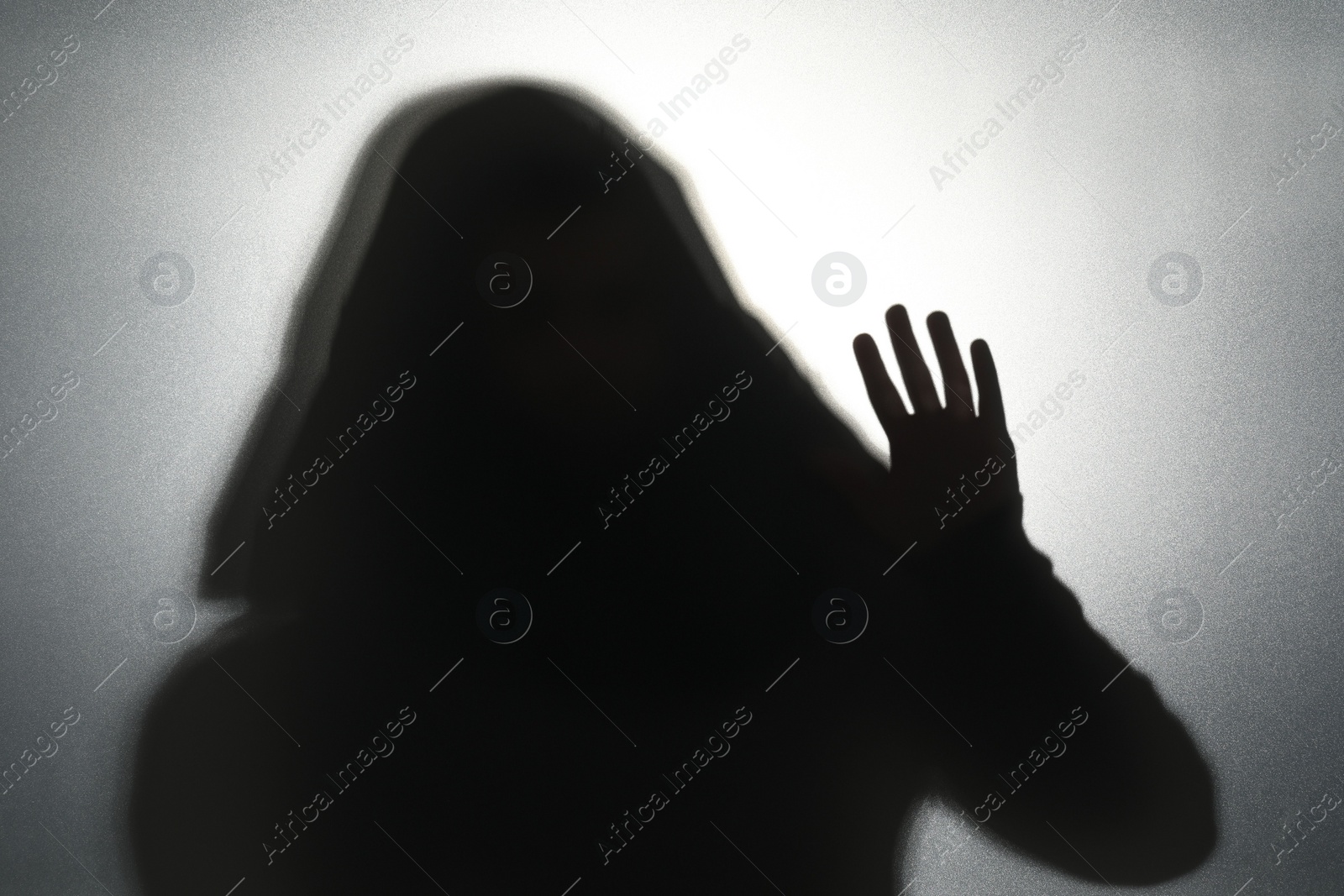 Photo of Silhouette of ghost behind glass against grey background