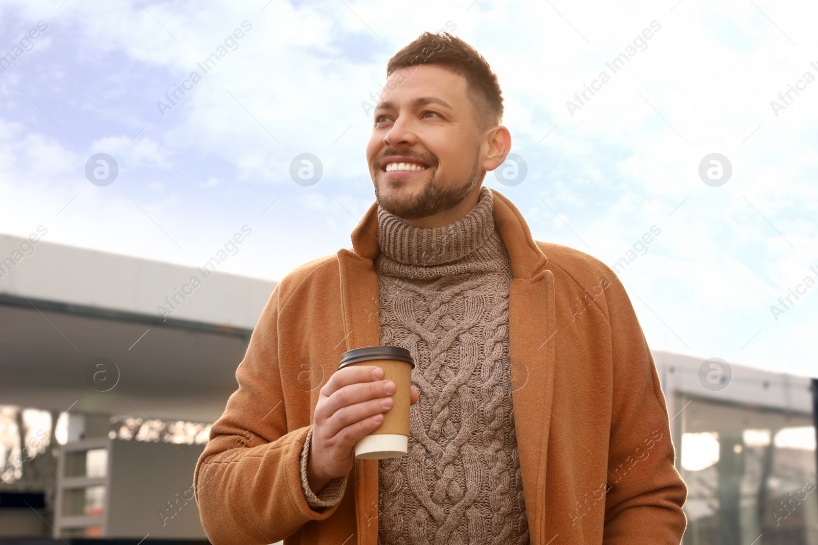 Photo of Man with cup of coffee on city street in morning