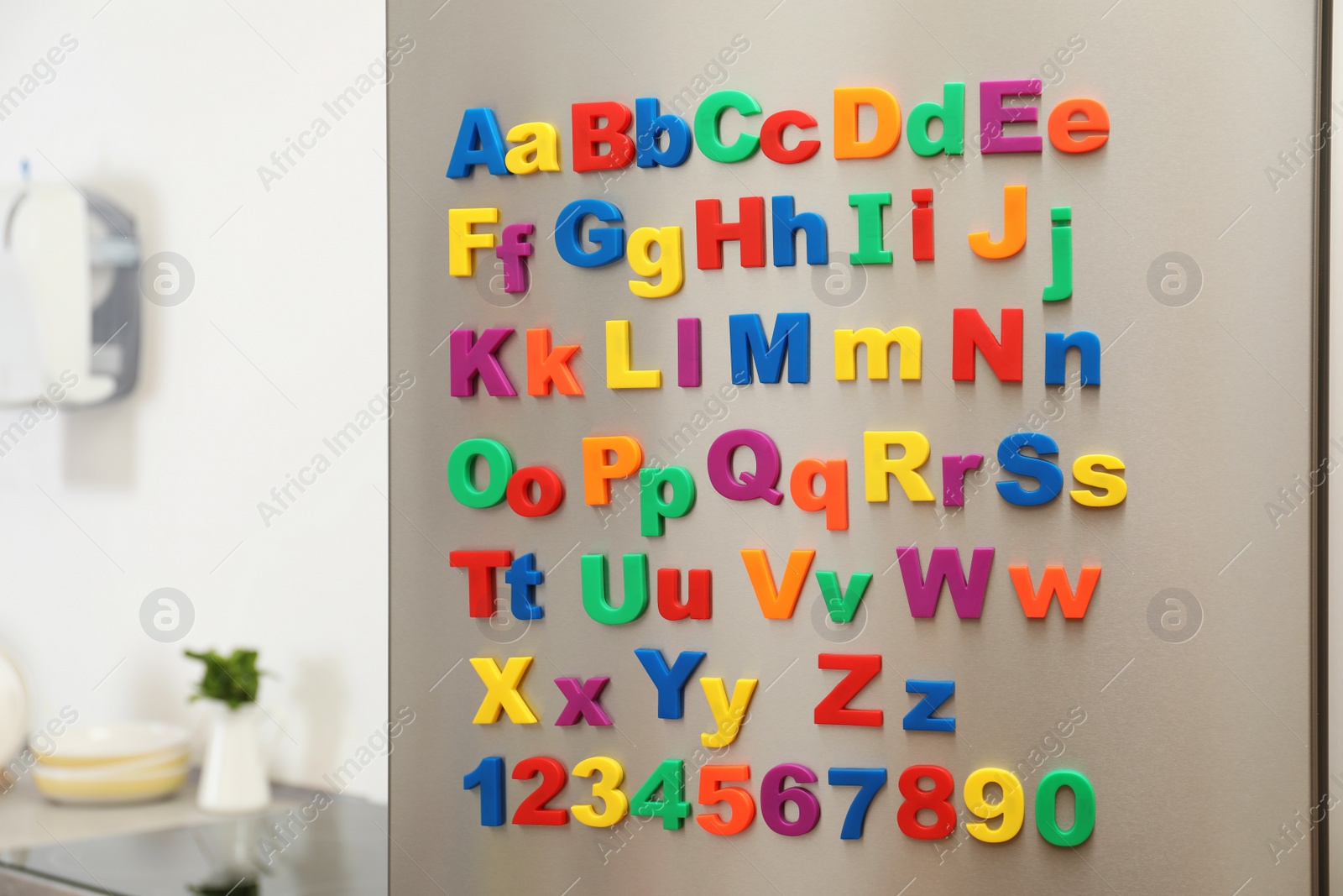 Photo of Refrigerator door with colorful magnetic letters and numbers in kitchen. Space for text