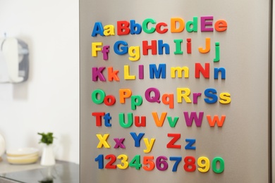 Photo of Refrigerator door with colorful magnetic letters and numbers in kitchen. Space for text