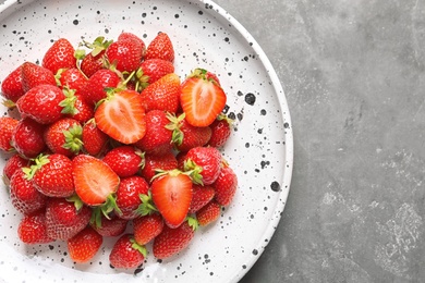 Plate with ripe strawberries on grey background, top view