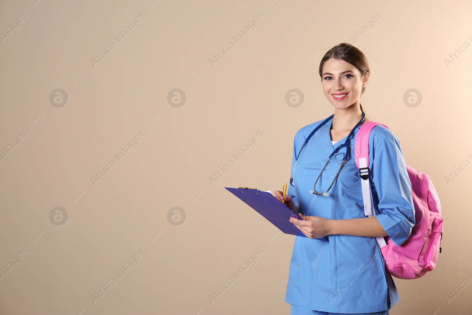 Photo of Young medical student with clipboard and backpack on color background. Space for text