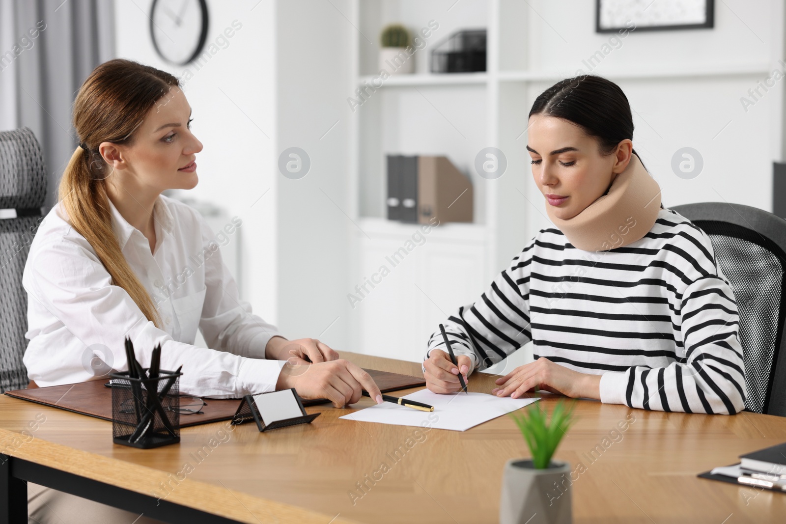 Photo of Injured woman signing document in lawyer's office