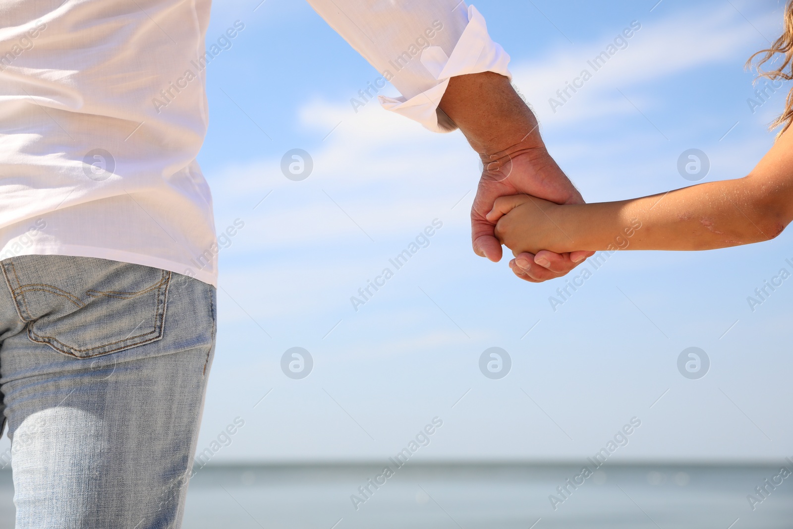 Photo of Little girl with grandfather near sea, closeup