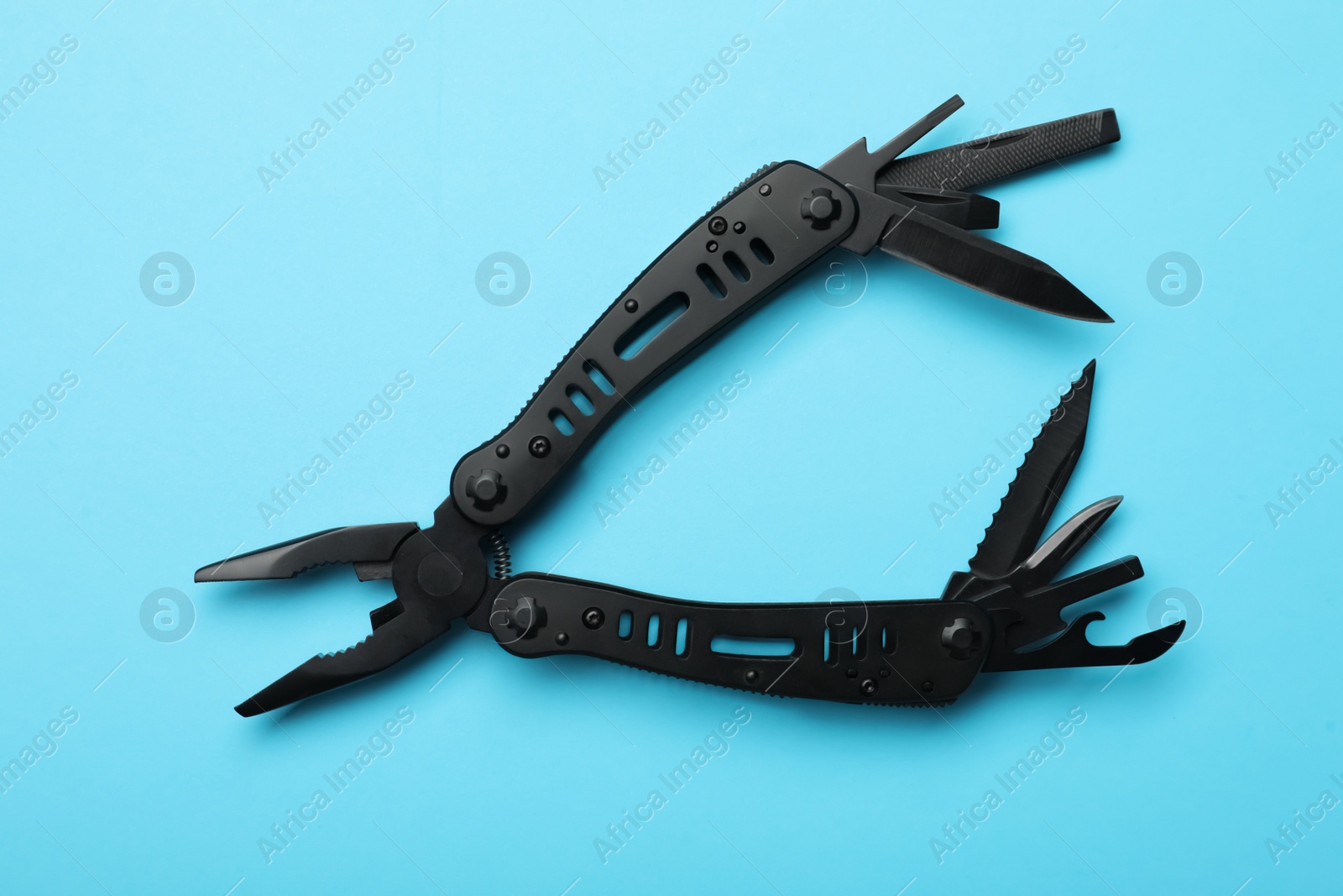 Photo of Compact portable black multitool on light blue background, top view