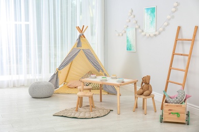 Cozy kids room interior with table, play tent and toys