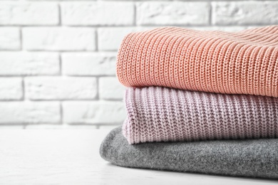 Photo of Stack of warm knitted clothes on table