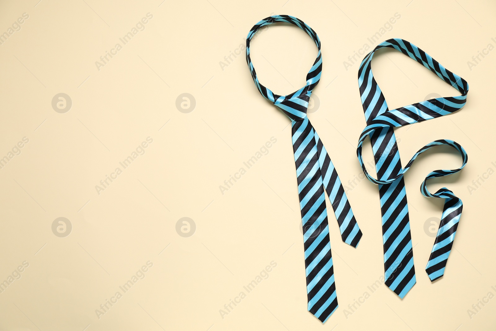 Photo of Striped neckties on beige background, top view. Space for text