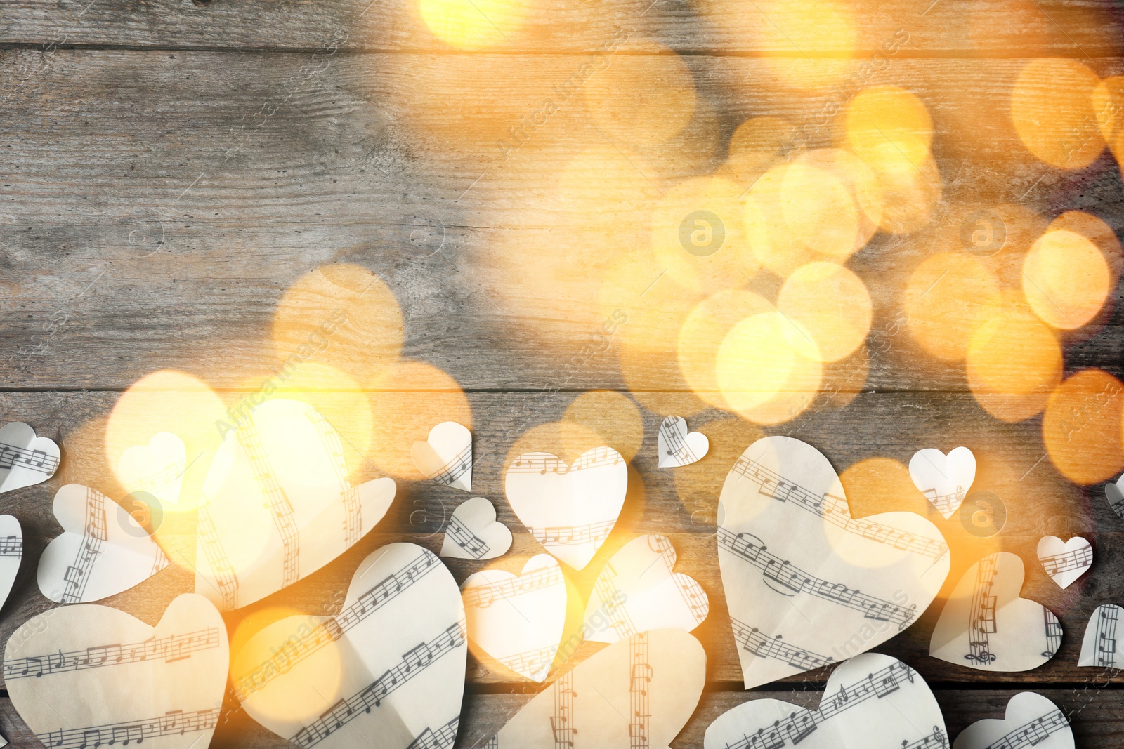 Image of Christmas and New Year music. Hearts cut out from music sheets on wooden background, bokeh effect