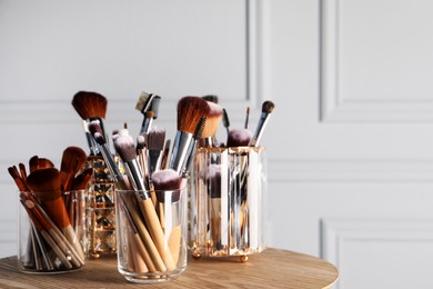Photo of Set of professional makeup brushes on wooden table, space for text