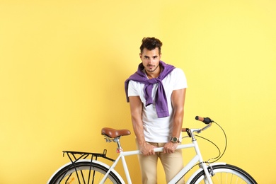 Photo of Handsome young hipster man with bicycle on yellow background