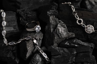 Photo of Luxury jewelry. Stylish presentation of elegant ring and bracelets on coal