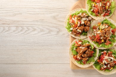 Photo of Delicious tacos with vegetables and meat on white wooden table, top view. Space for text