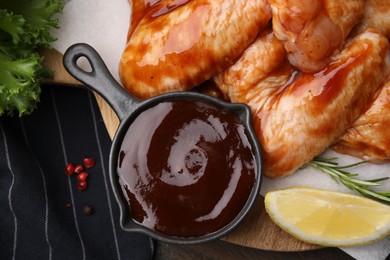 Photo of Fresh marinade, raw chicken wings and lemon on table, top view