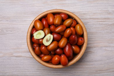 Photo of Fresh Ziziphus jujuba fruits in bowl on wooden table, top view