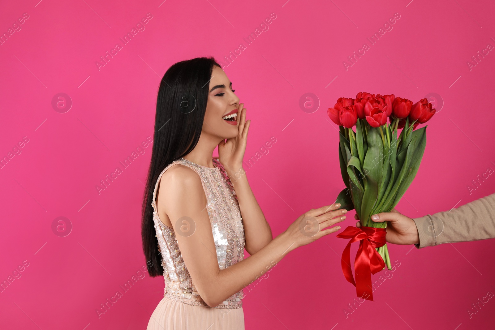Photo of Happy woman receiving red tulip bouquet from man on pink background. 8th of March celebration