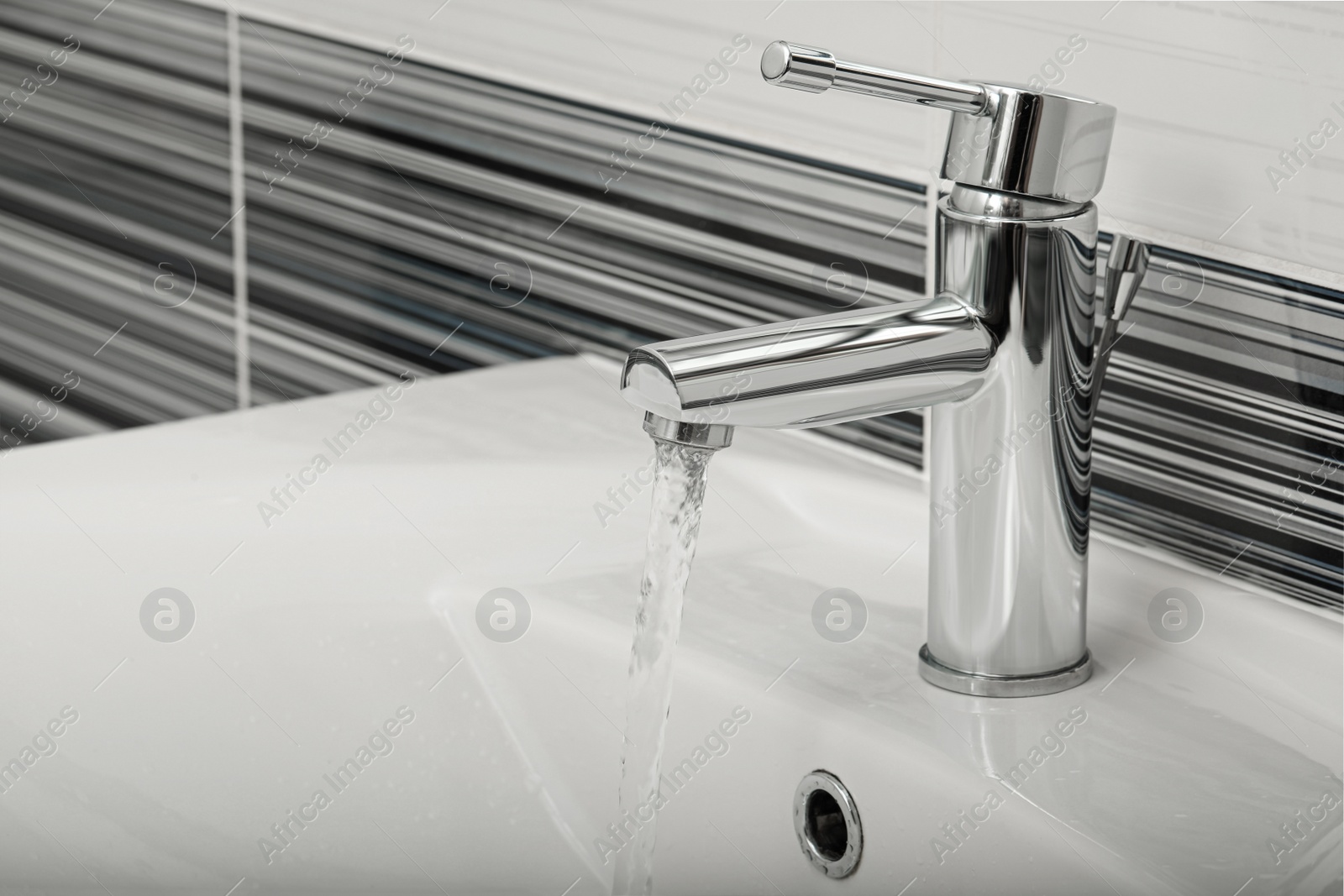 Photo of Stream of water flowing from tap in bathroom