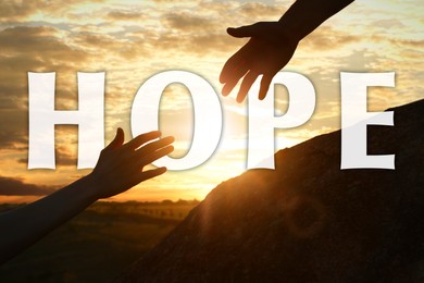 Image of Concept of hope. Man helping woman to climb on hill at sunset, closeup