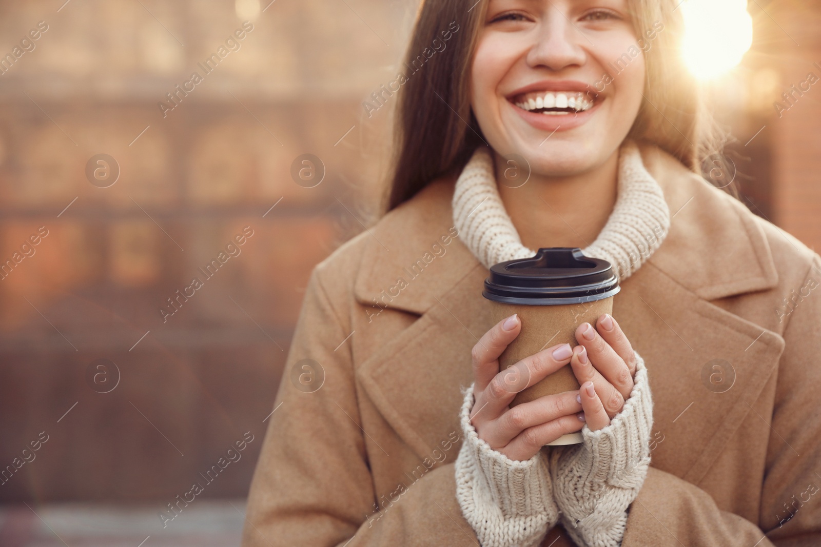 Photo of Young woman with cup of coffee on city street in morning, closeup