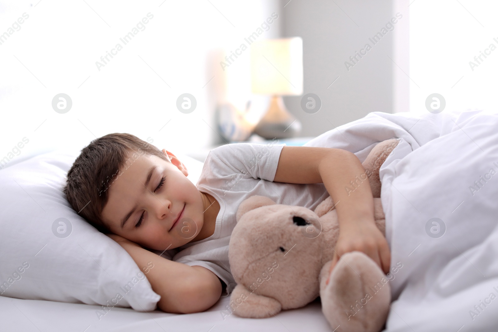 Photo of Little boy sleeping with teddy bear at home. Bedtime