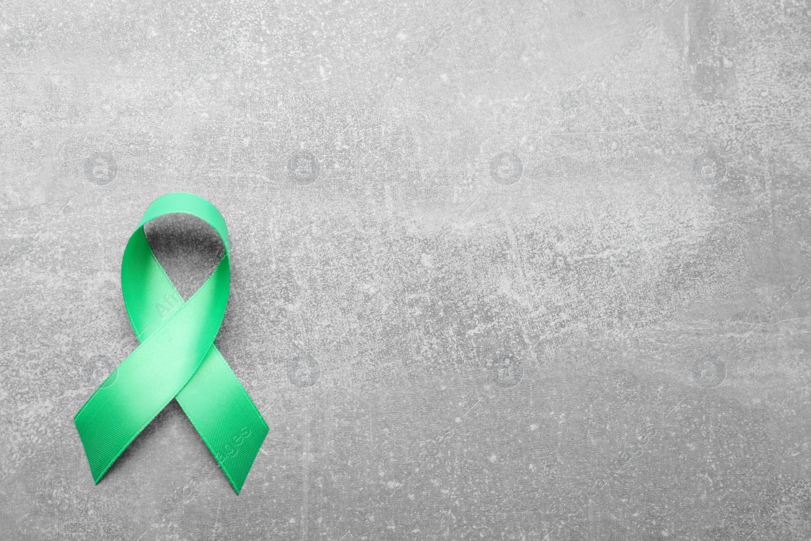 Photo of World Mental Health Day. Green ribbon on light grey background, top view with space for text