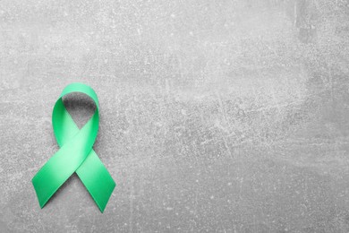 Photo of World Mental Health Day. Green ribbon on light grey background, top view with space for text