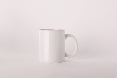 Photo of Blank white ceramic mug on light background