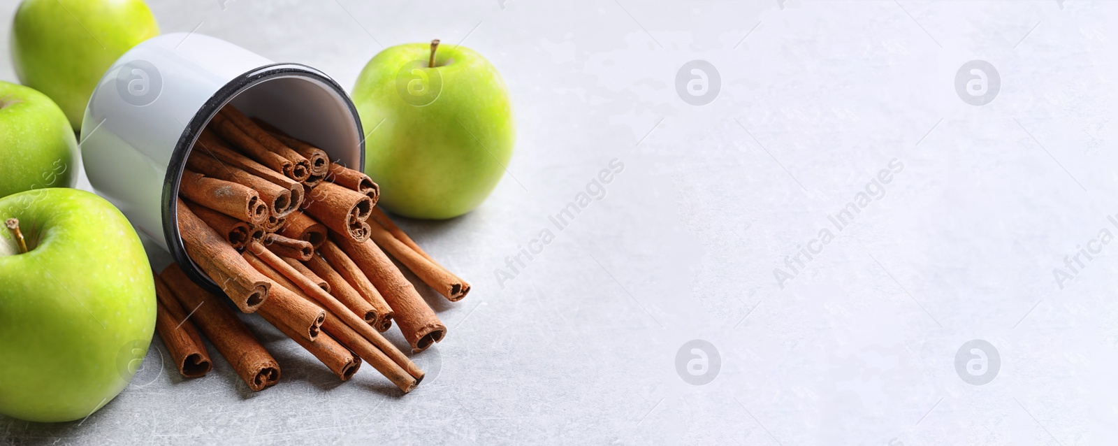 Image of Fresh apples and mug with cinnamon sticks on table, space for text. Banner design