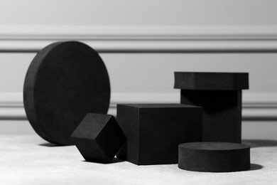 Black geometric figures on light grey table. Stylish presentation for product