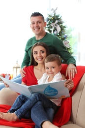 Happy parents and child reading fairy tales together at home on Christmas day