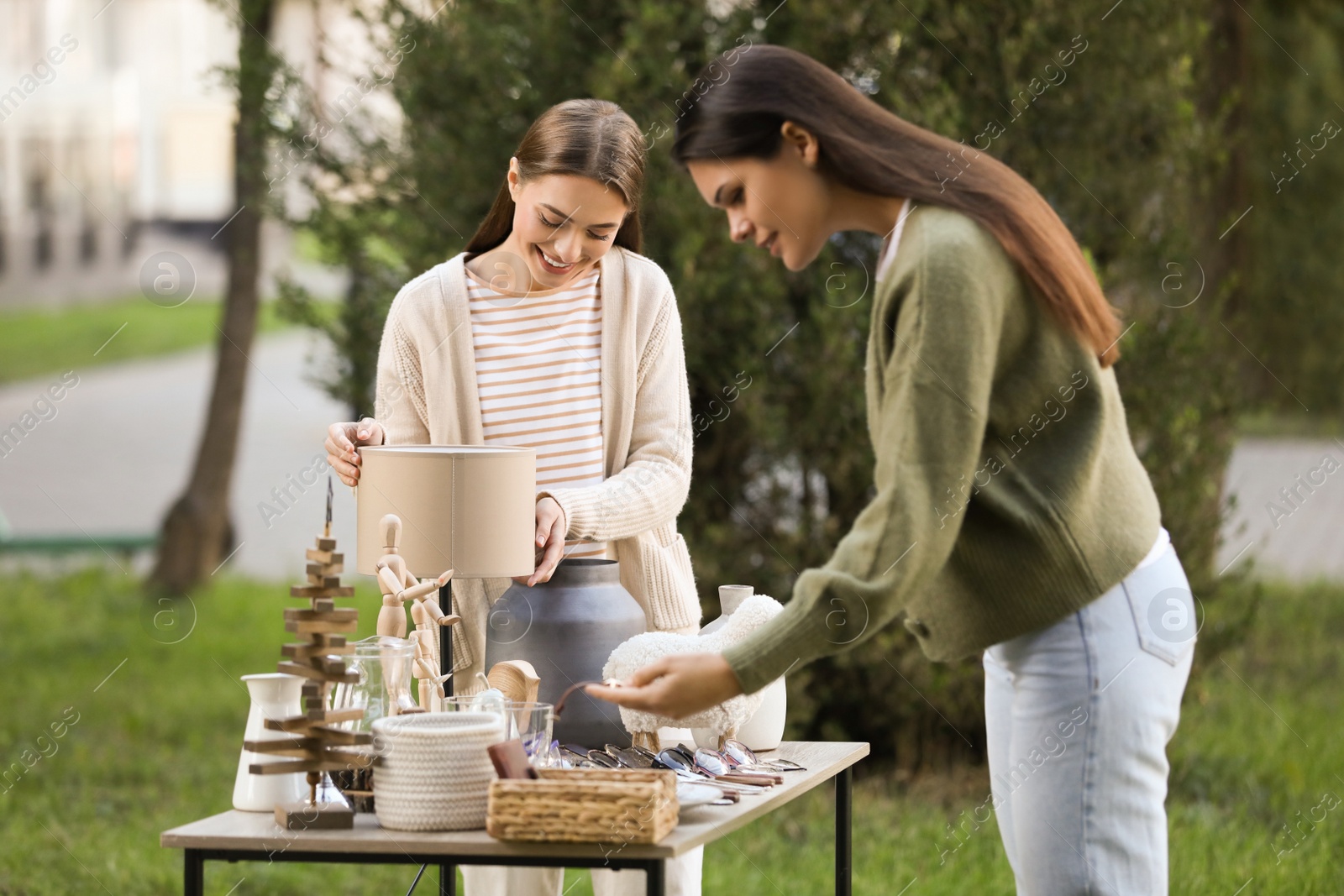 Photo of Women shopping at table in yard. Garage sale