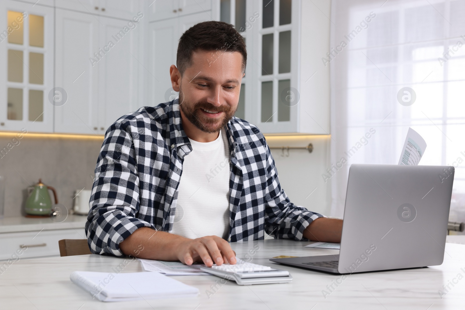 Photo of Man calculating taxes at table in kitchen