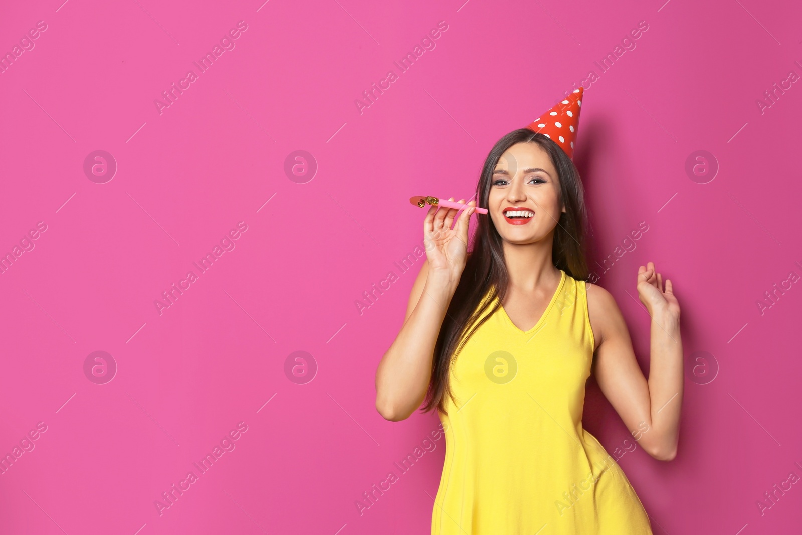 Photo of Young woman with party blower on color background. Birthday celebration