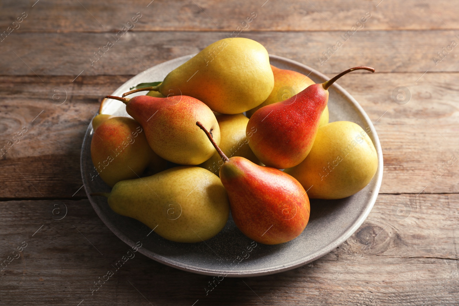 Photo of Plate with ripe pears on wooden background