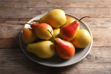 Photo of Plate with ripe pears on wooden background