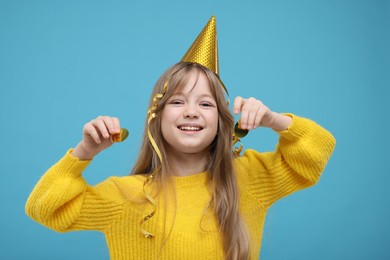 Photo of Happy little girl in party hat with confetti on light blue background