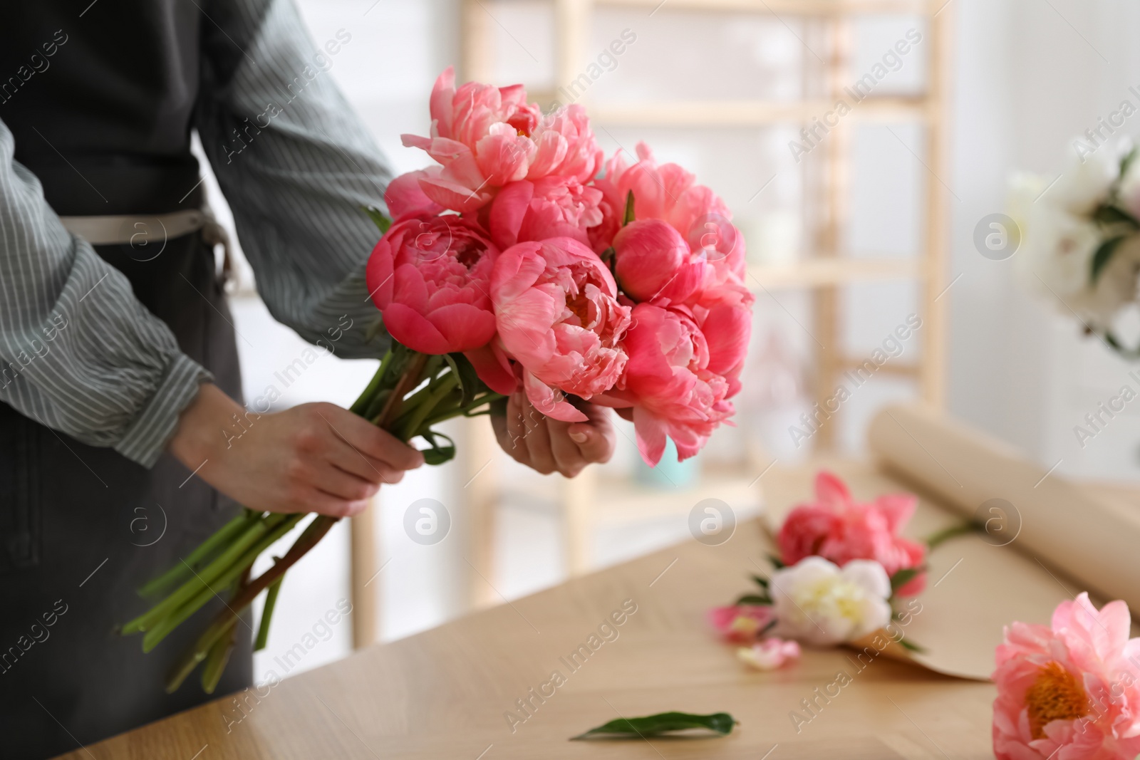 Photo of Florist making beautiful peony bouquet at table, closeup