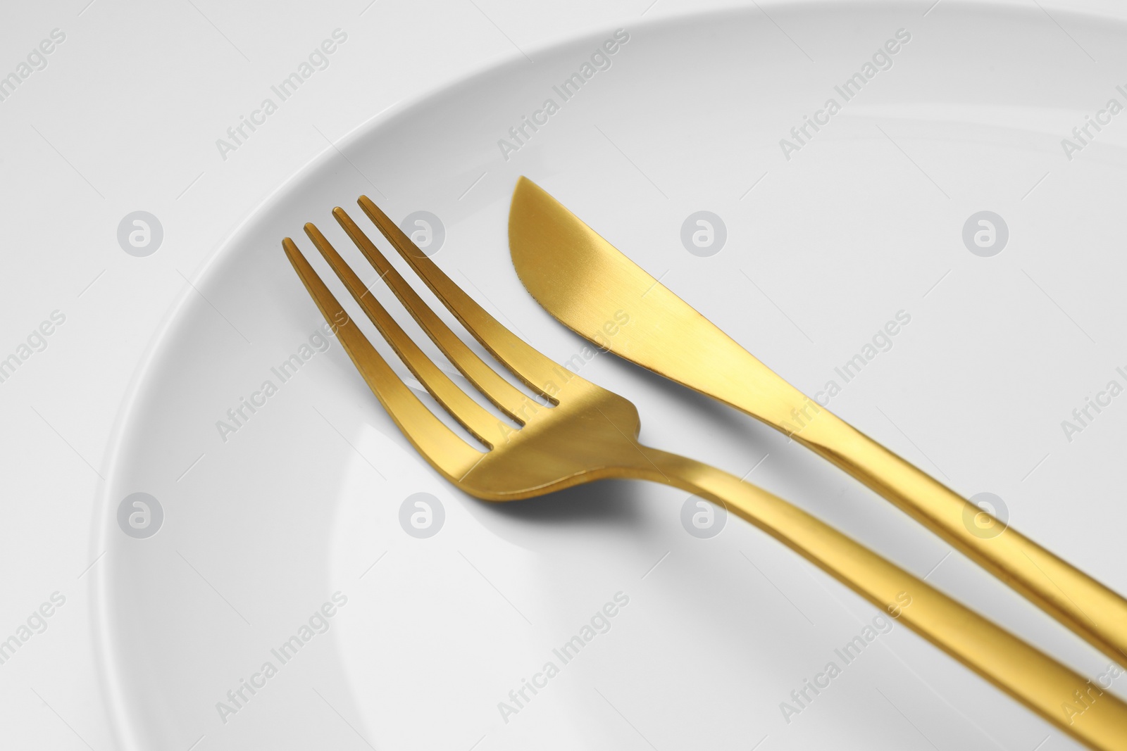 Photo of Clean plate, fork and knife on white background, closeup