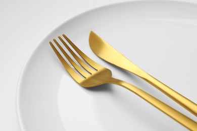 Photo of Clean plate, fork and knife on white background, closeup