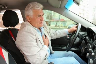 Senior man suffering from heart attack in car