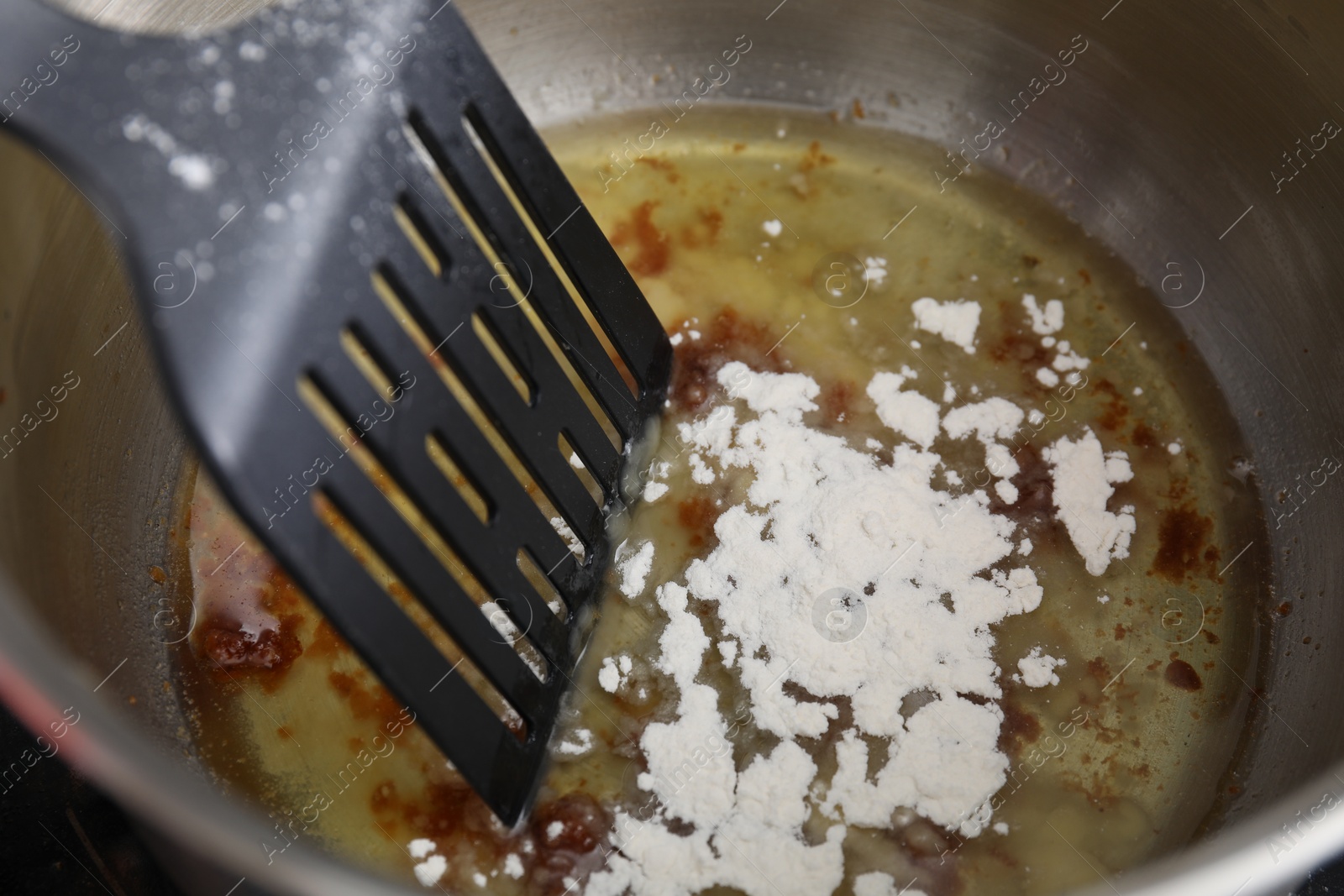 Photo of Cooking delicious turkey gravy. Ingredients and spatula in pot, closeup