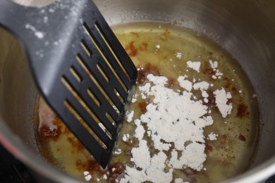 Photo of Cooking delicious turkey gravy. Ingredients and spatula in pot, closeup